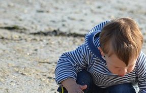 Kind op stand met zand spelen 